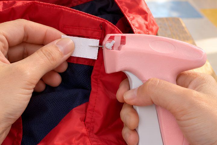 Attaching a name label inside a red kids' jacket with the Quick Stitch